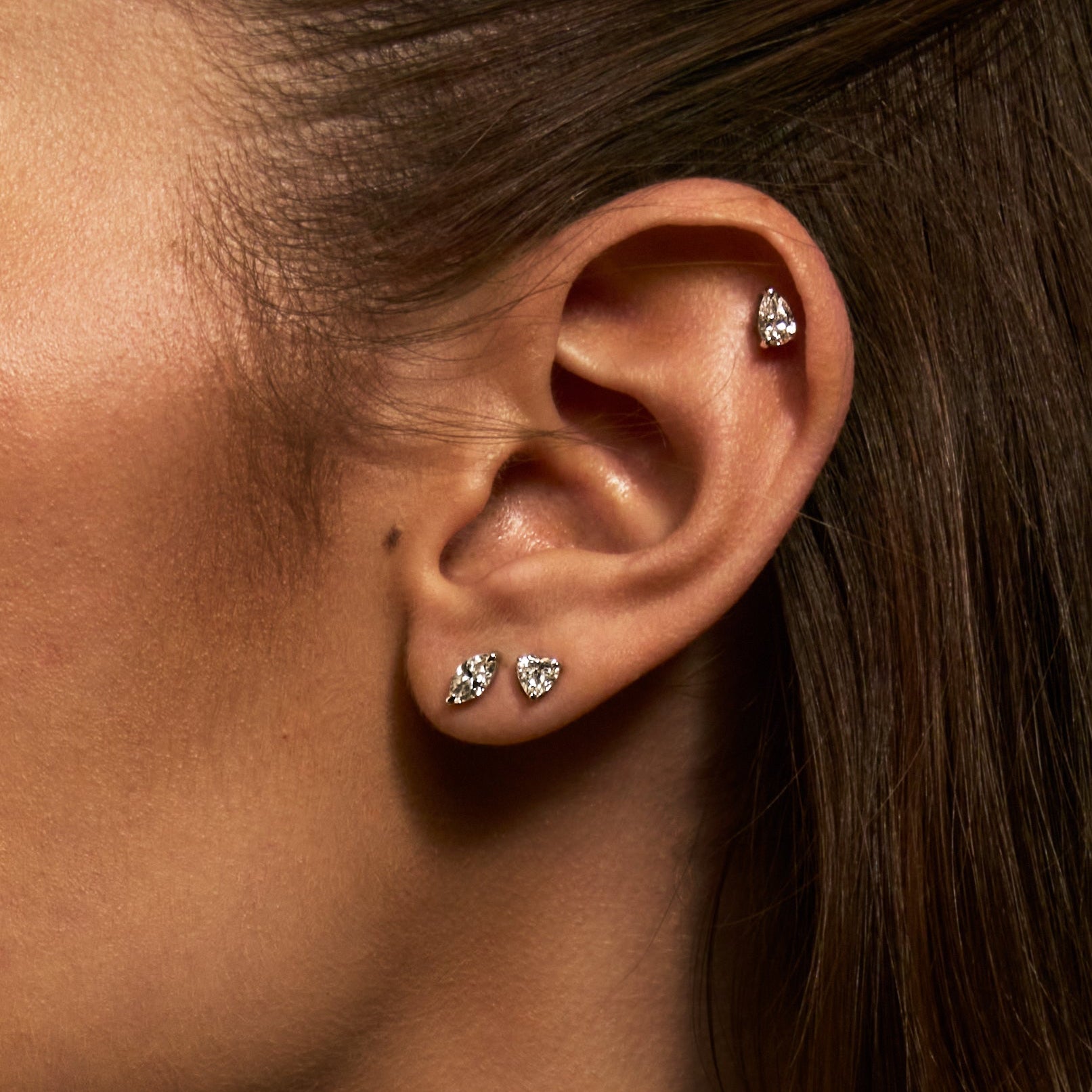 Close-up of an ear wearing diamond stud earrings with a blurred background