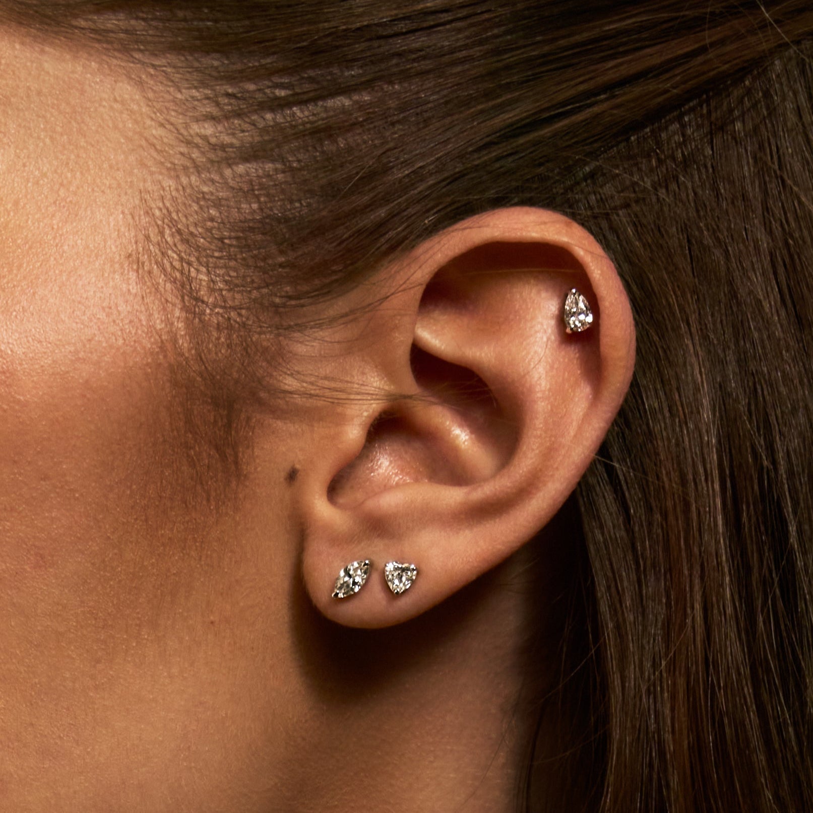 Close-up of an ear wearing diamond stud earrings with a blurred background