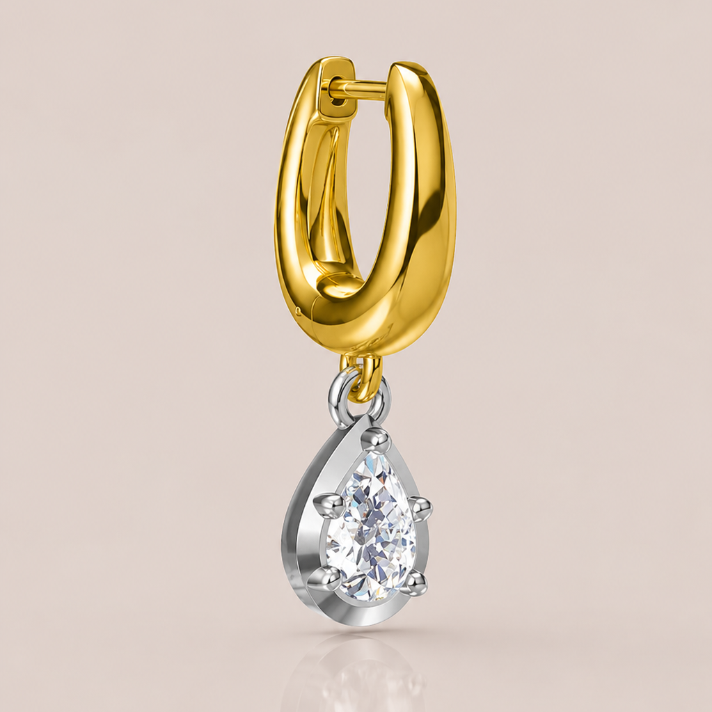 Gold hoop earring with a teardrop-shaped diamond pendant on a beige background