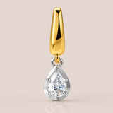 Gold and silver teardrop-shaped pendant on a beige background
