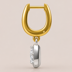 Gold and silver earring with a diamond on a beige background