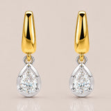 A pair of gold and silver drop earrings, each featuring a polished gold teardrop-shaped top and a pear-cut clear gemstone in a silver bezel setting below, shown on a light beige background.