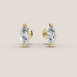 Pair of gold earrings with clear gemstones on a beige background