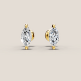 Pair of gold earrings with clear gemstones on a beige background
