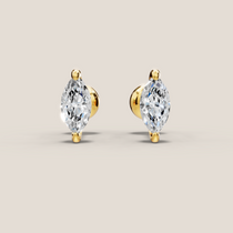 Pair of gold earrings with clear gemstones on a beige background