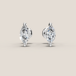 Pair of marquise-shaped diamond earrings on a beige background