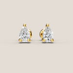 Pair of pear-shaped diamond earrings with gold settings on a beige background