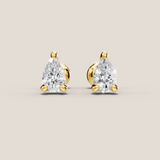 Pair of pear-shaped diamond earrings with gold settings on a beige background