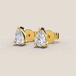 Gold earrings with pear-shaped gemstones on a beige background