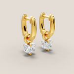 Gold hoop earrings with heart-shaped gemstones on a light beige background