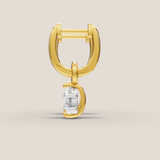 Gold earring with a clear gemstone on a beige background