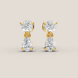 Gold and diamond earrings on a beige background
