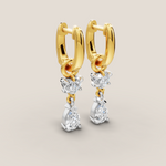 Gold hoop earrings with diamond drops on a beige background