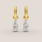 Gold earrings with teardrop-shaped diamonds on a beige background