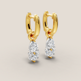 Gold hoop earrings with diamond drops on a beige background