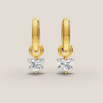 Gold hoop earrings with heart-shaped diamond drops on a beige background