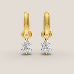 Gold earrings with diamond drops on a beige background