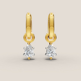 Gold earrings with diamond drops on a beige background