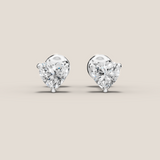 Heart-shaped diamond earrings on a beige background