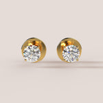 Gold earrings with clear gemstones on a beige background