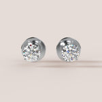 Pair of diamond stud earrings on a light beige background