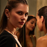 Woman looking at herself in a mirror with another woman in the background
