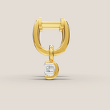Gold earring with a clear gemstone on a beige background