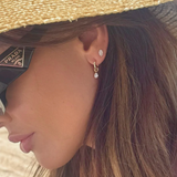 Close-up of a person wearing a Prada handbag, straw hat, and diamond earrings.