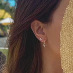 Close-up of a person wearing diamond earrings with a blurred outdoor background