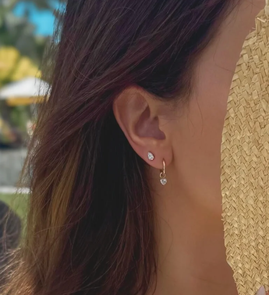 Close-up of a person wearing diamond earrings with a blurred outdoor background