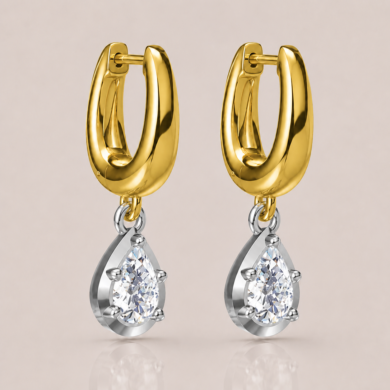 A pair of gold huggie hoop earrings with silver-toned settings holding clear teardrop-shaped gemstones, shown on a soft beige background.